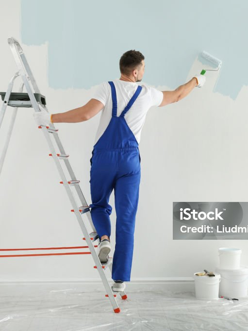 Maler auf einer Leiter streicht eine Wand