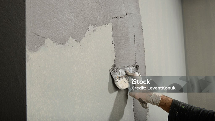Glättkelle zieht Spachtelmasse an einer Wand ab